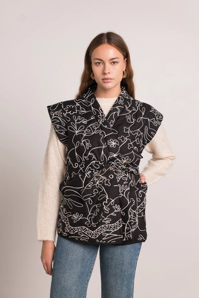 Veste sans manches noire avec des motifs blancs, taille unique, disponible également dans nos concepts store de Bruxelles