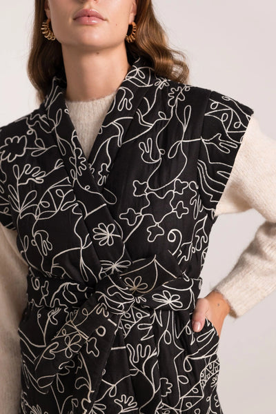 Veste sans manches noire avec des motifs blancs, taille unique, disponible également dans nos concepts store de Bruxelles